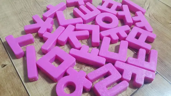 Набор пластиковых букв алфавита помещен на деревянный пол — стоковое фото