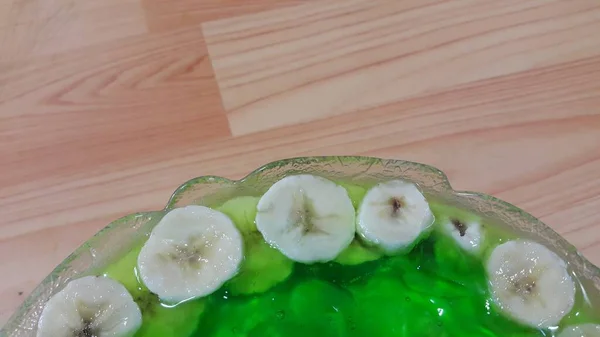 Kremowy smaczny słodki zielony galaretka z plasterkami bananów warstwowych na powierzchni — Zdjęcie stockowe