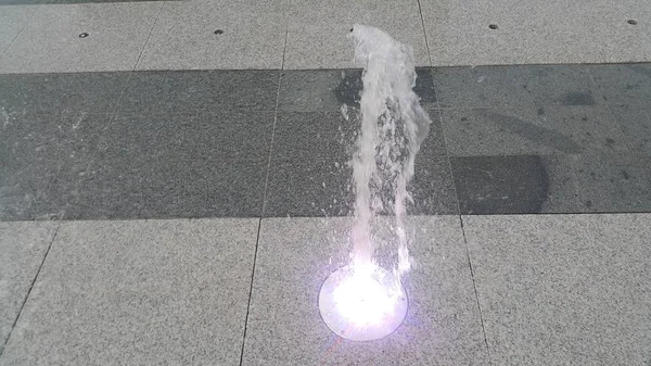 Bella e colorata fontana d'acqua leggera sul pavimento di cemento — Foto Stock