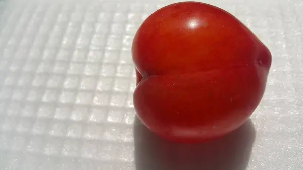 Vue rapprochée de prune rouge sur fond gris blanc — Photo