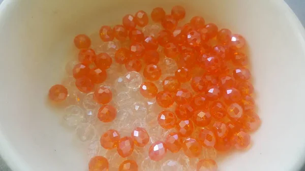 Shining, transparent, orange color crystal beads or gemstones in a bowl — Stock Photo, Image