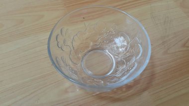 Ahşap zemindeki boş cam kaselerin en üst görüntüsü. Duvarında çiçekler olan cam bir kase.