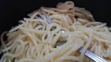 Gümüş çatal ile bir kase içinde dönen noodle veya spagetti makarna görünümü yakın