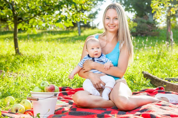 Ibu cantik dengan bayi duduk di luar ruangan di atas selimut — Stok Foto