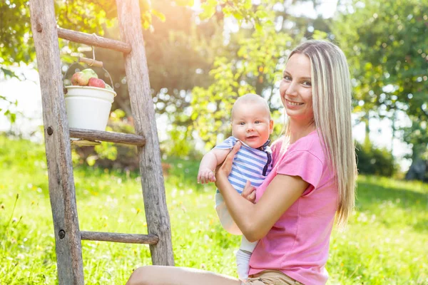 Madre con el bebé recogiendo manzanas de un manzano —  Fotos de Stock