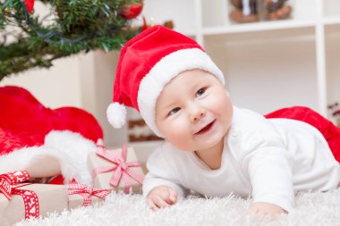 Noel Baba şapkası ile Noel ağacı yanında sevimli bebek sunar