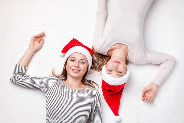 Retrato de hermanas felices tiradas en el suelo con sombreros de Navidad —  Fotos de Stock