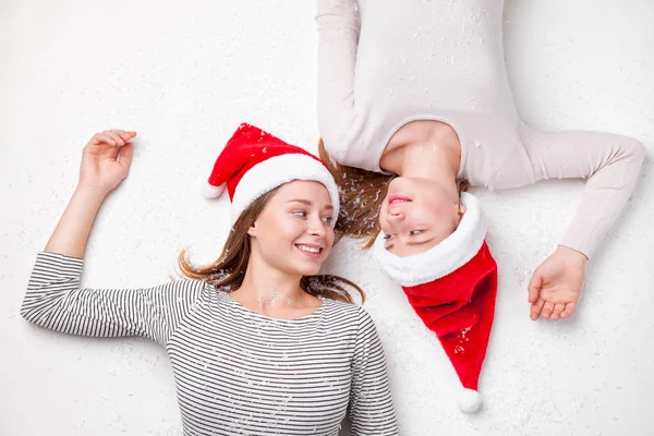 Portrait de sœurs heureuses allongées sur le sol portant des chapeaux de Noël — Photo