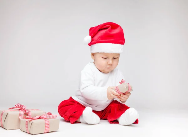 Schattig baby dragen een kerstmuts openen Kerst presenteert — Stockfoto
