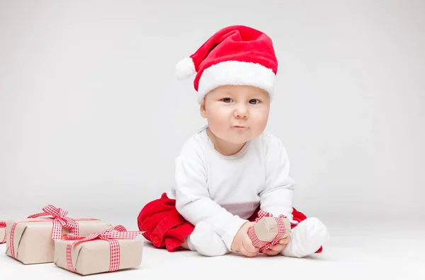 Bebek Noel açılış Noel Baba şapkası giyen sunar — Stok fotoğraf