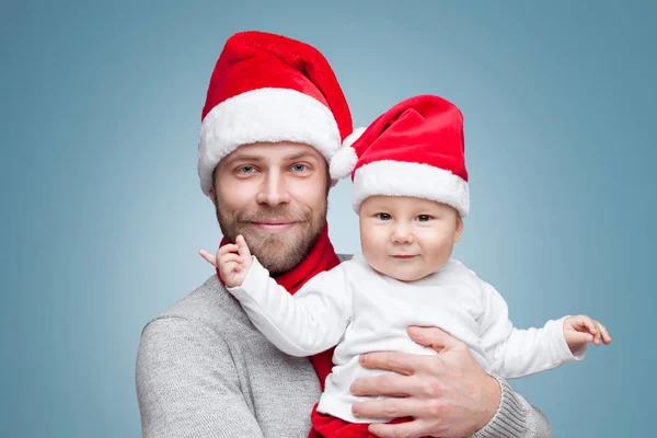 Pai com menino vestindo chapéus de Papai Noel celebrando o Natal — Fotografia de Stock