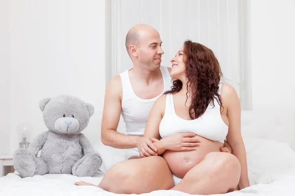 Encantados padres jóvenes en la cama esperando un bebé —  Fotos de Stock