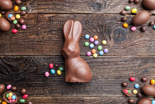Шоколадний великодній кролик, яйця та цукерки на сільському фоні — стокове фото