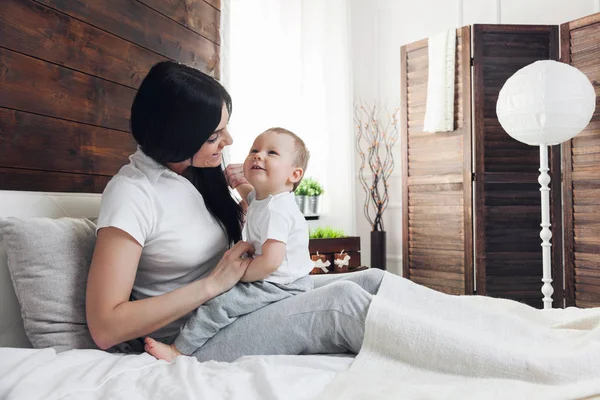 Lycklig mamma med hennes söta barn på sängen med en bra tid — Stockfoto