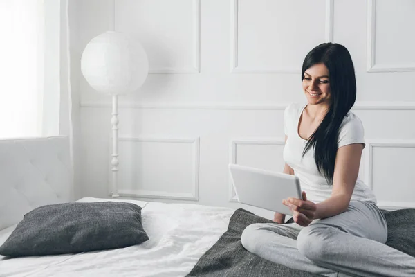 Mooie vrouw ontspannen op het bed en het gebruik van haar tablet — Stockfoto