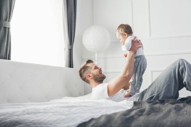 Mutlu baba oğluyla evde yatakta oynamak