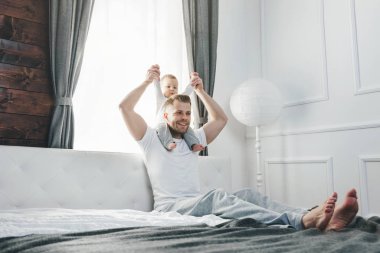 Mutlu baba oğluyla evde yatakta oynamak