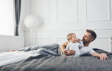 Mutlu baba oğluyla evde yatakta oynamak