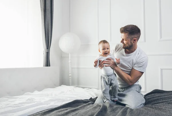 Happy father with his son playing at home on the bed — Stock Photo, Image