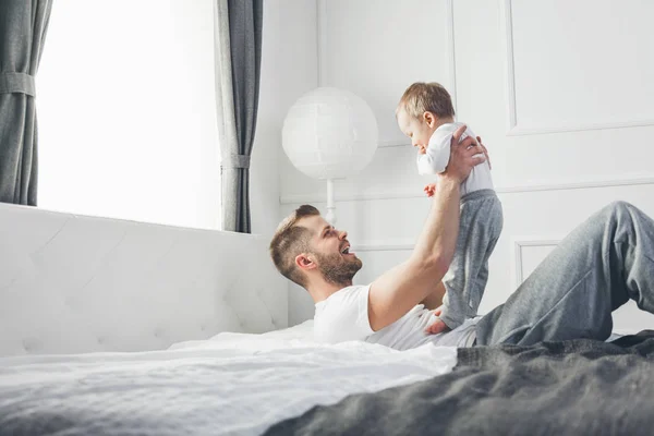 Lycklig far med sin son som spelar hemma på sängen — Stockfoto
