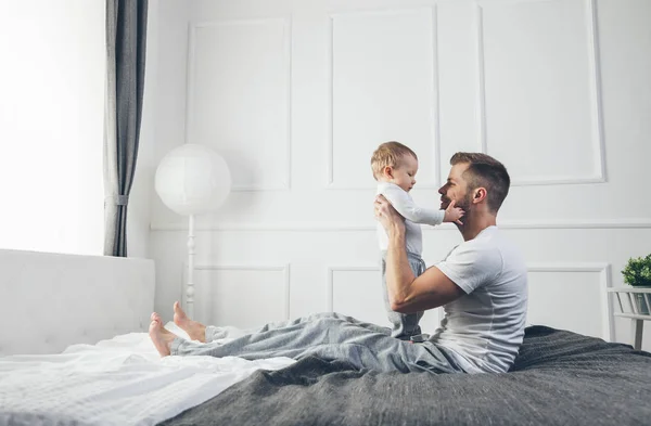 Lycklig far med sin son som spelar hemma på sängen — Stockfoto