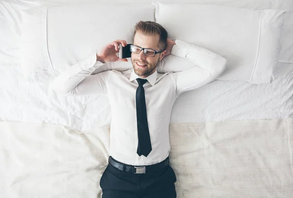 Ansicht von oben. schöner Geschäftsmann mit Brille auf dem Bett liegend — Stockfoto