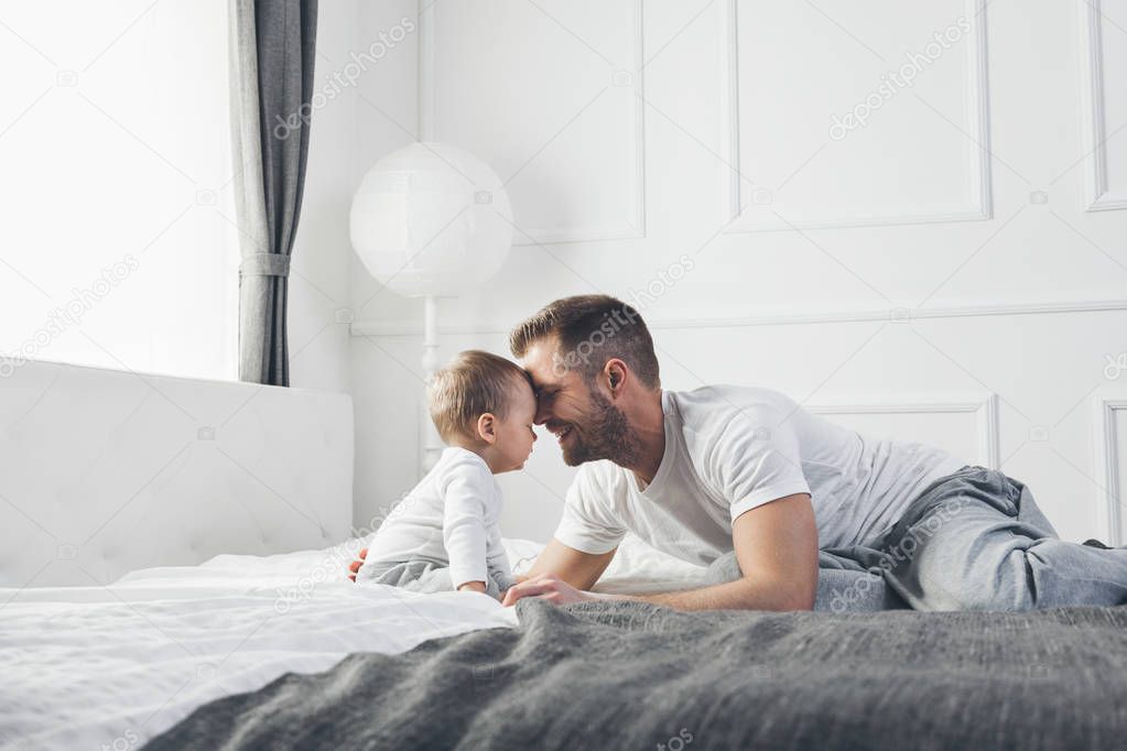 Happy father with his son playing at home on the bed