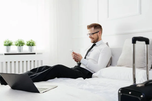 Empresario trabajando desde una habitación de hotel con su teléfono móvil — Foto de Stock