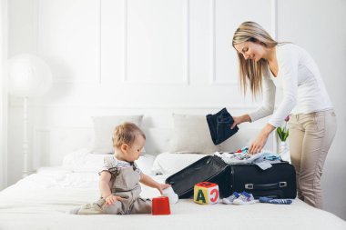 Çocuklarla seyahat. Mutlu anne çocuğunu giyim tatil için ambalaj ile