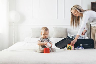 Çocuklarla seyahat. Mutlu anne çocuğunu giyim tatil için ambalaj ile