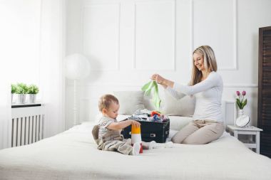 Çocuklarla seyahat. Mutlu anne çocuğunu giyim tatil için ambalaj ile