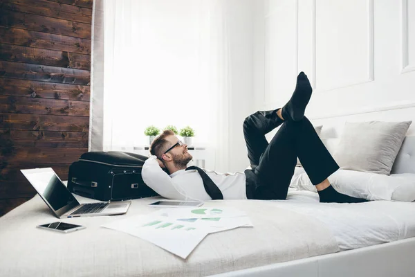 Empresario en la cama trabajando con un portátil desde su habitación de hotel — Foto de Stock