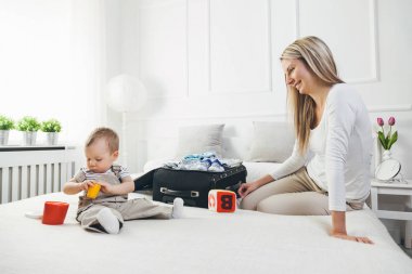 Çocuklarla seyahat. Mutlu anne çocuğunu giyim tatil için ambalaj ile