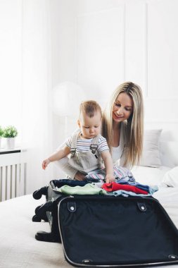 Çocuklarla seyahat. Mutlu anne çocuğunu giyim tatil için ambalaj ile