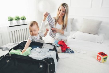 Çocuklarla seyahat. Mutlu anne çocuğunu giyim tatil için ambalaj ile