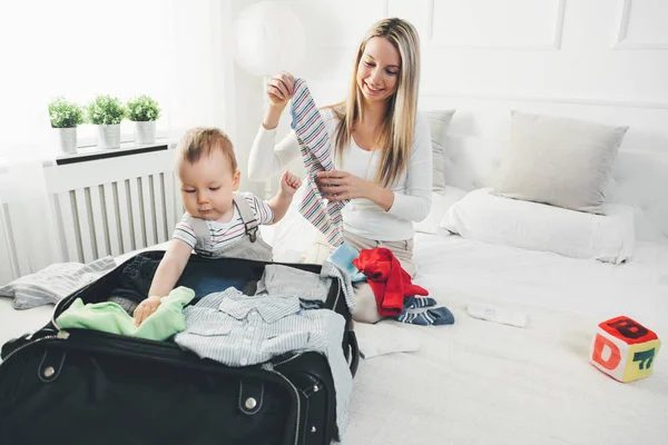 Viajando con niños. Madre feliz con su hijo empacando ropa para las vacaciones — Foto de Stock