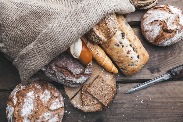 Delicioso pan fresco dentro de un saco sobre fondo de madera — Foto de Stock