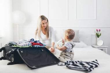 Çocuklarla seyahat. Mutlu anne çocuğunu giyim tatil için ambalaj ile