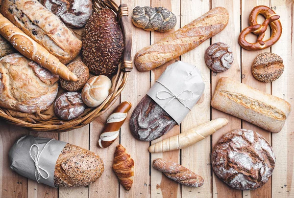 Bir sepet ahşap arka plan üzerinde lezzetli taze ekmek dolu — Stok fotoğraf