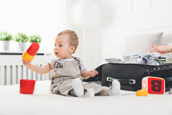 Podróżowanie z dziećmi. Ładny maluch pakowania ubrań i zabawki na wakacje — Zdjęcie stockowe