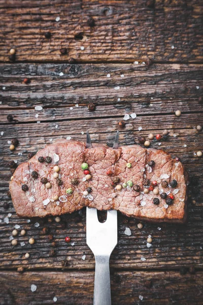 Delicious grilled steak with seasoning on wooden background — Stock Photo, Image