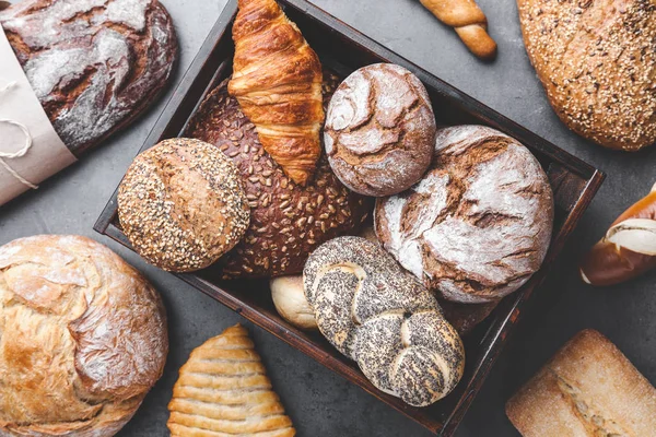 Bir sepet ahşap arka plan üzerinde lezzetli taze ekmek dolu — Stok fotoğraf