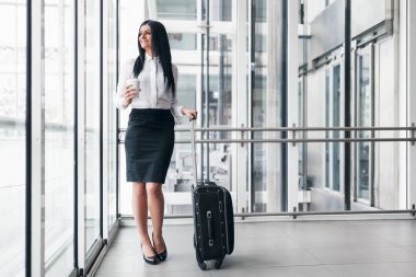 Kahve ve bavul bir ofis ortamında başarılı iş kadını