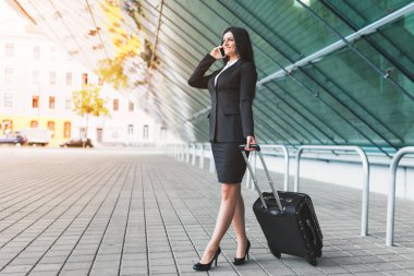 Genç iş kadını ile cep telefonu ve bavul kentsel ortamda