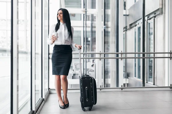 Successful business woman with coffee and suitcase in an office setting — Stock Photo, Image
