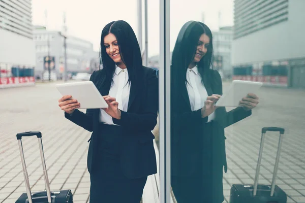 Joven empresaria con tablet y maleta en un entorno urbano — Foto de Stock