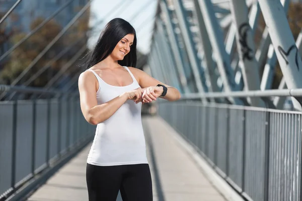 Entraînement en ville. Belle femme avec une formation smartwatch dans un cadre urbain — Photo