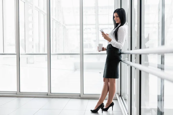 Erfolgreiche Geschäftsfrau mit Kaffee und Smartphone im Büro — Stockfoto