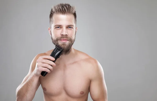 Stilig skäggig man trimma skägget med en trimmer — Stockfoto