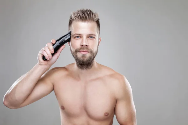 Hombre guapo cortando su propio pelo con un cortador — Foto de Stock